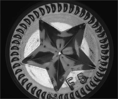 Source capture of a moulded bottle base under a white dome light: central star, a ring of curved moulded marks and a raised two-character code. Complete capture, not retouched.