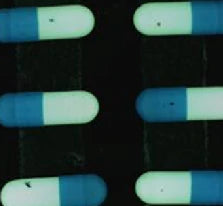 White LS-DL12570 arch-light capture: capsules against a dark background, with a visible dark mark on a light capsule surface.