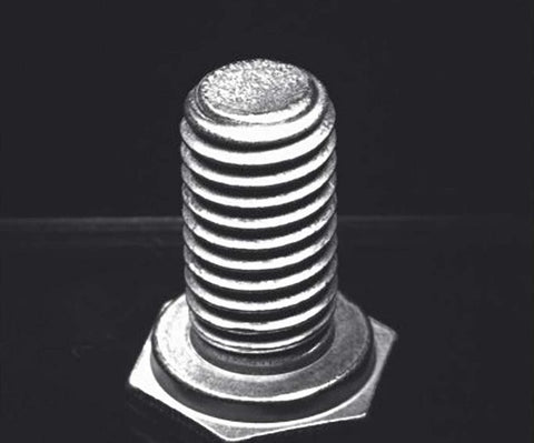 Source capture of a hex bolt standing on its head under a blue ring light: bright thread crests, dark roots and the end face on top. Complete capture inside the brochure frame, not retouched.