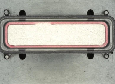 Source colour capture of a rectangular metal frame part under a white dome light: a pink-red glue band all round the inner rectangle. Cropped at the top to remove a stamped number; not retouched.