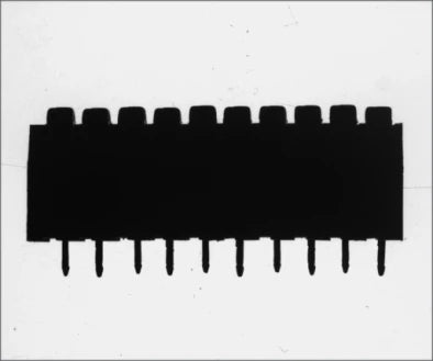 Source side silhouette of a dual-in-line package on a blue parallel backlight: black body and a row of ten leads on a bright field. Complete capture, not retouched.
