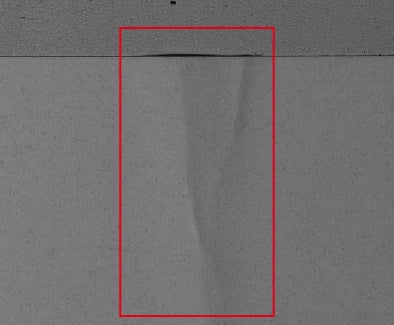 Oblique line-light capture of the same label application; the crease region stands out more strongly.