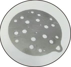 The test part: a circular machined metal plate with drilled holes.