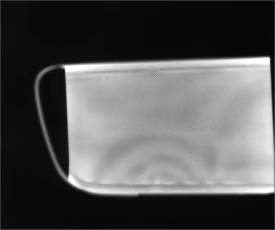 Source white flat-coaxial capture: the reflective face shows broad brightness variation and a visible outer boundary. No particular pit is labelled.