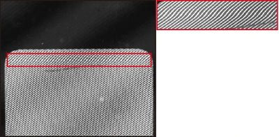 Camera capture under the white LS-2LFM100. The original red annotation and inset show the local stripe deformation at the crease.