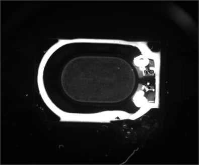 Source UV loudspeaker capture: a bright adhesive region follows much of the perimeter of the dark central assembly.
